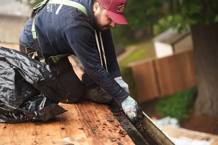 Sunnyside Roofing worker clearing a residential gutter